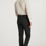 Man wearing a beige shirt and charcoal pants on a white background