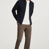 Man wearing a navy jacket, white shirt, brown pants, and sunglasses on a white background
