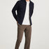 Man wearing a navy jacket, white shirt, brown pants, and sunglasses on a white background