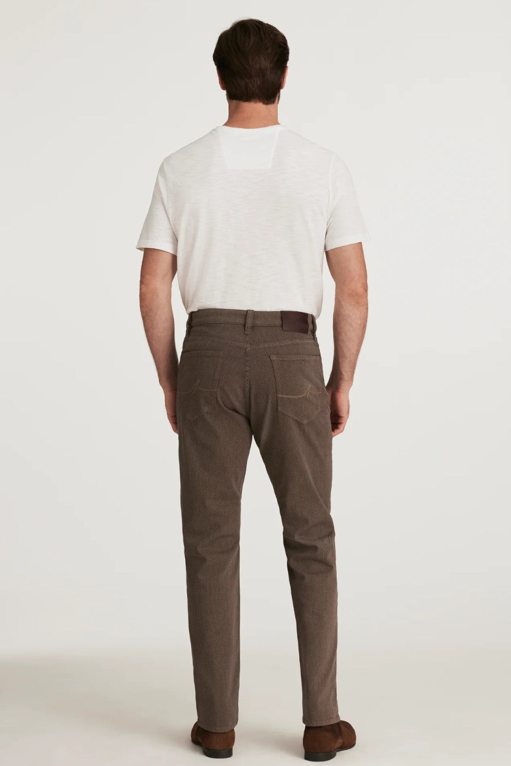 Man wearing brown pants and a white shirt on a white background