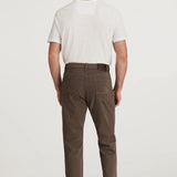 Man wearing brown pants and a white shirt on a white background