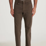 Person wearing brown pants and a white shirt on a plain background