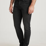 Person wearing black jeans and brown shoes on a white background