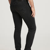 Person wearing black jeans and brown shoes on a white background