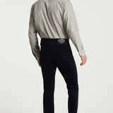 Man wearing a light gray shirt and dark jeans on a white background