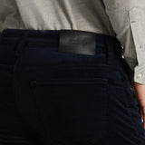 Person wearing dark blue pants with a visible brand logo on the waistband.