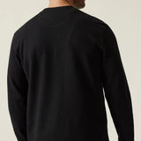 Man wearing a black long-sleeve shirt against a plain background