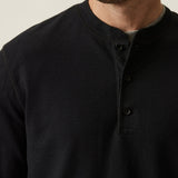 Man wearing a black long-sleeve shirt against a neutral background