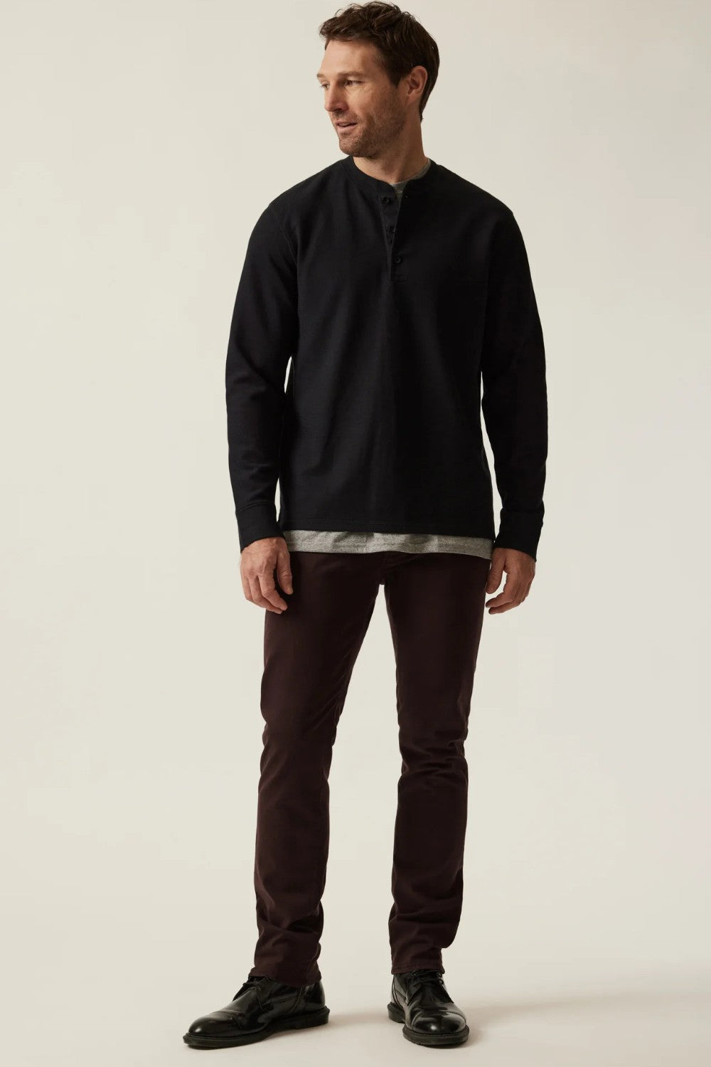 Man wearing a black long-sleeve shirt and dark pants on a white background