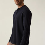 Man wearing a dark blue long-sleeve shirt against a plain background