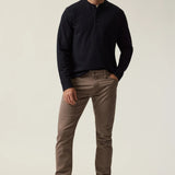 Man wearing a dark sweater and brown pants on a plain background