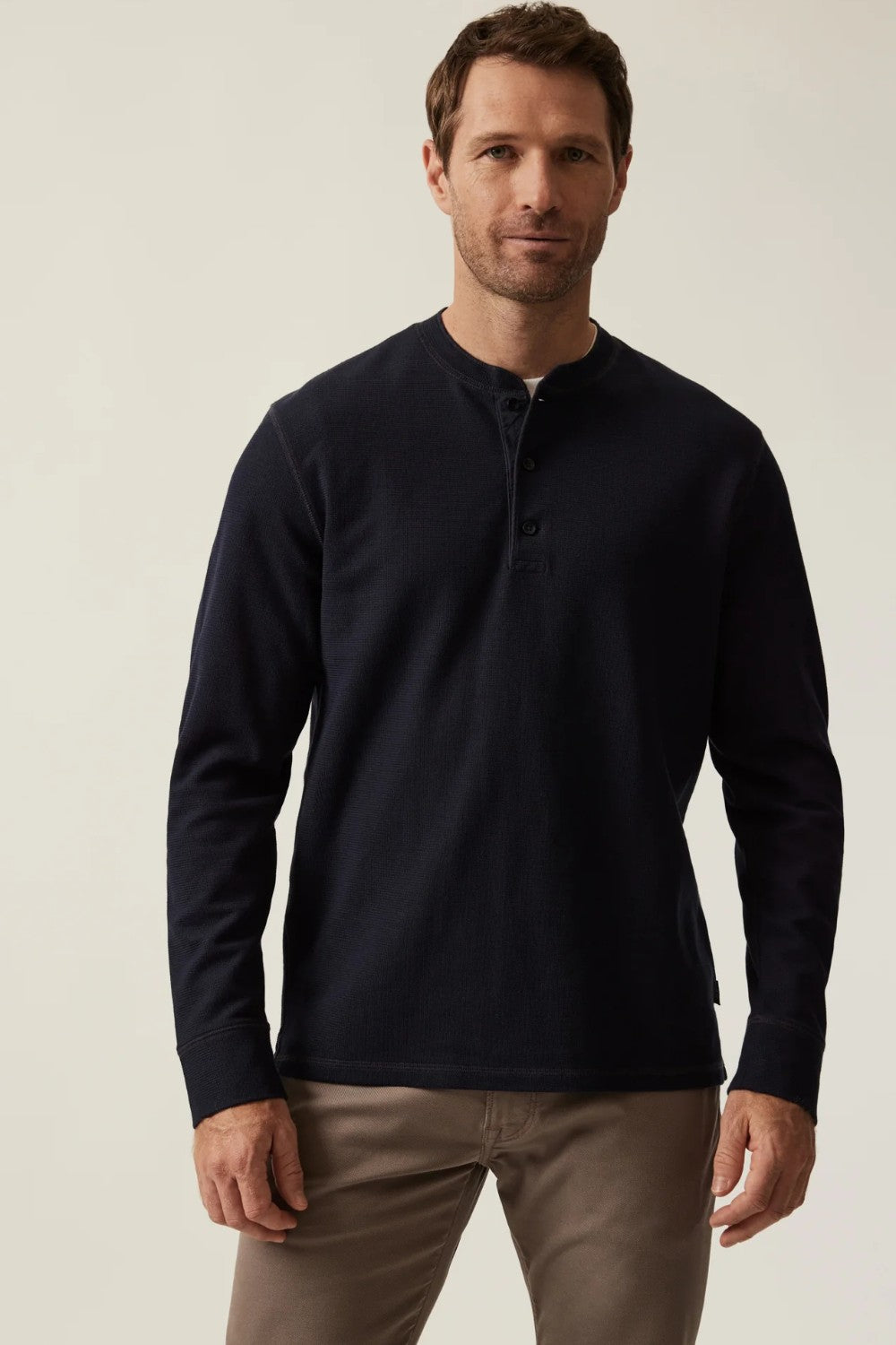 Man wearing a navy long-sleeve shirt against a beige background