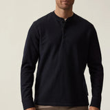 Man wearing a navy long-sleeve shirt against a beige background