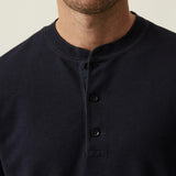 Man wearing a black henley shirt against a neutral background