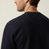 Man wearing a navy blue sweater against a beige background
