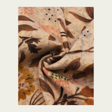 Floral printed scarf  in shades of brown, green and orange photographed on a light backdrop.