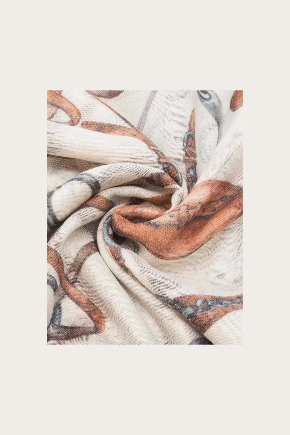 Close up of a cream coloured scarf with a brown and grey equestrian print photographed on a light background.