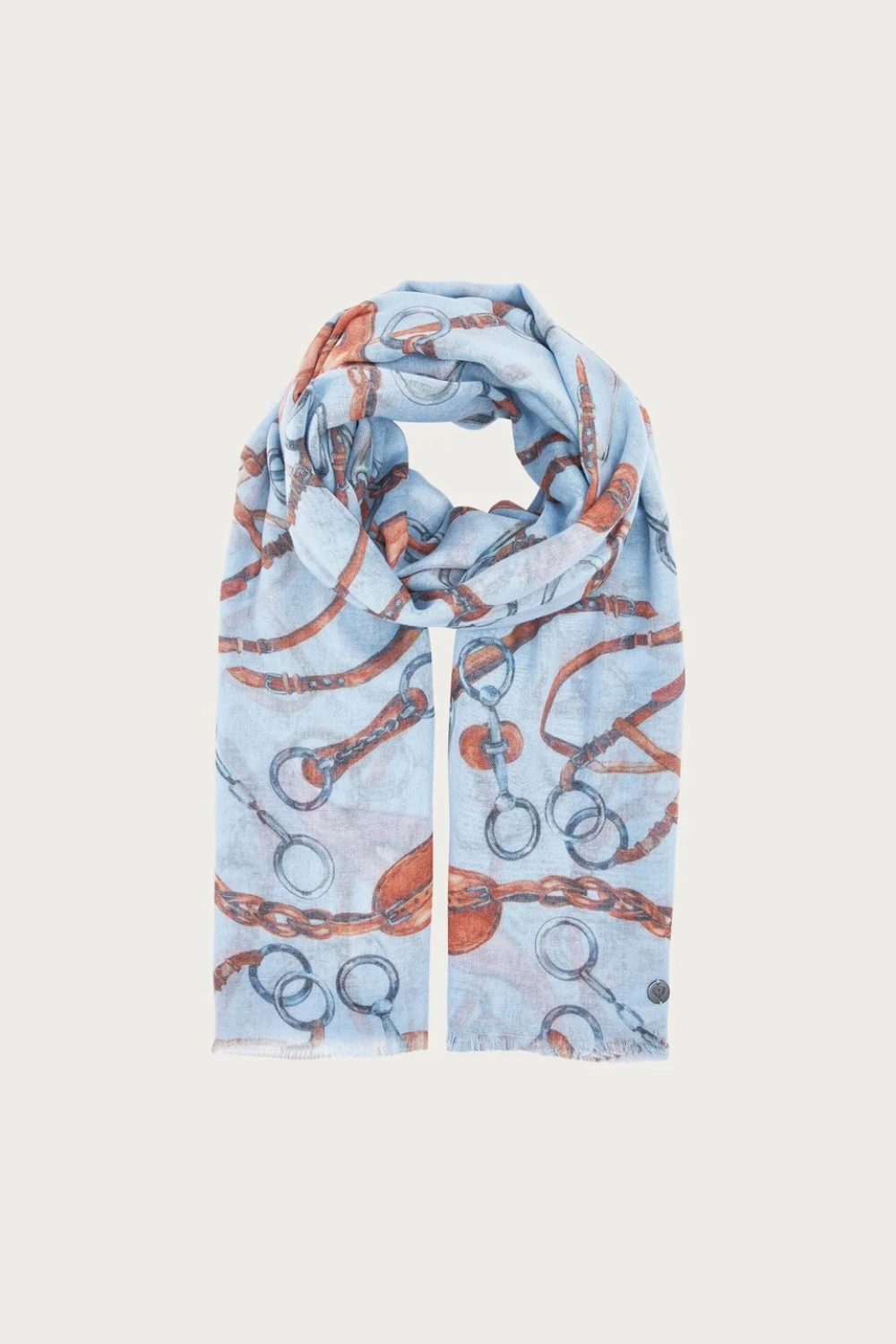 A light blue scarf with an allover print of horse bits and chains in rust orange and gray, styled in a loop on a light gray background.