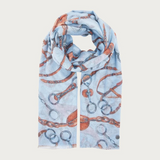 A light blue scarf with an allover print of horse bits and chains in rust orange and gray, styled in a loop on a light gray background.