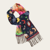 A multicolor patterned scarf with fringe, featuring a navy blue base with whimsical illustrations of stars and Christmas motifs, shown on a light beige background.