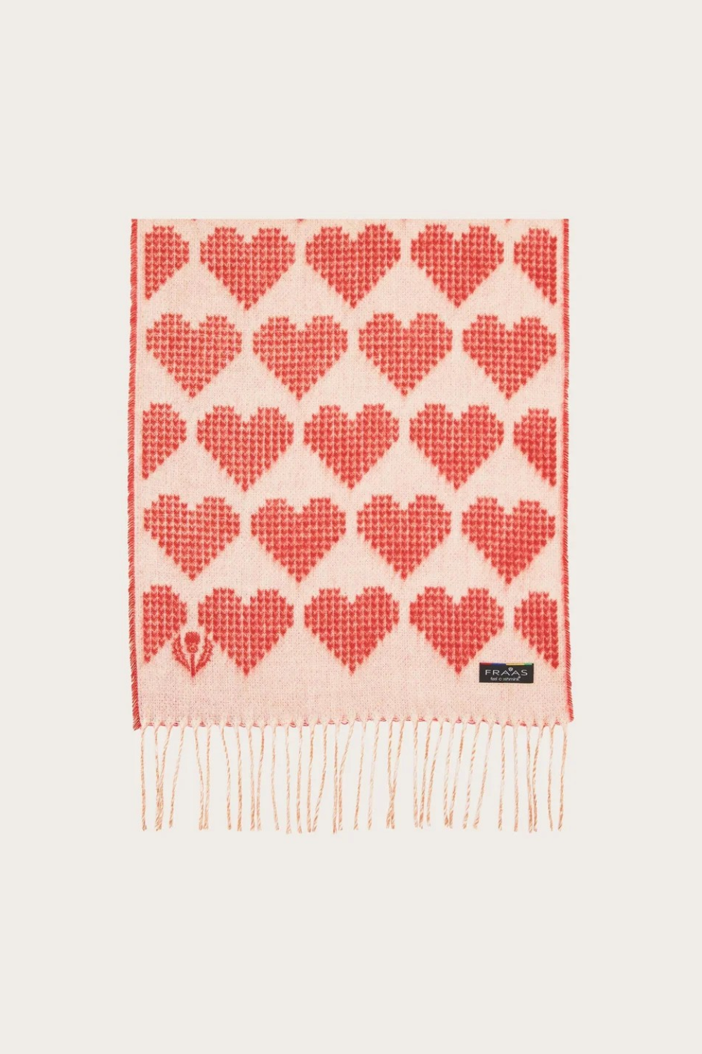 A red and cream heart printed scarf with fringe photographed on a light background.