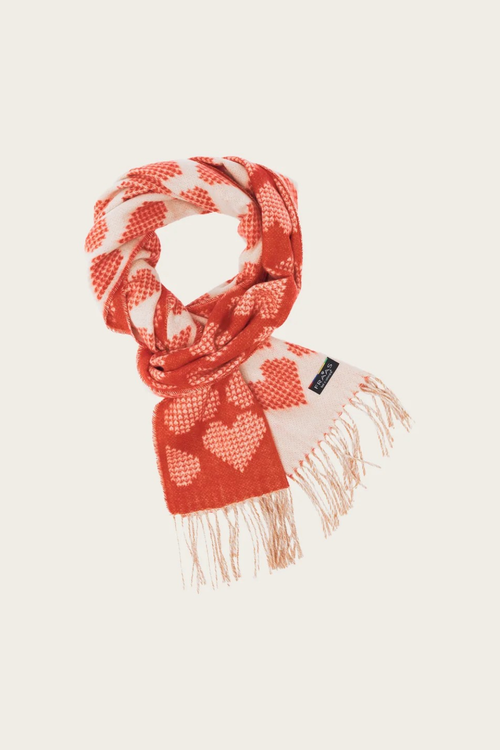 A red and cream heart printed scarf with fringe photographed on a light background.