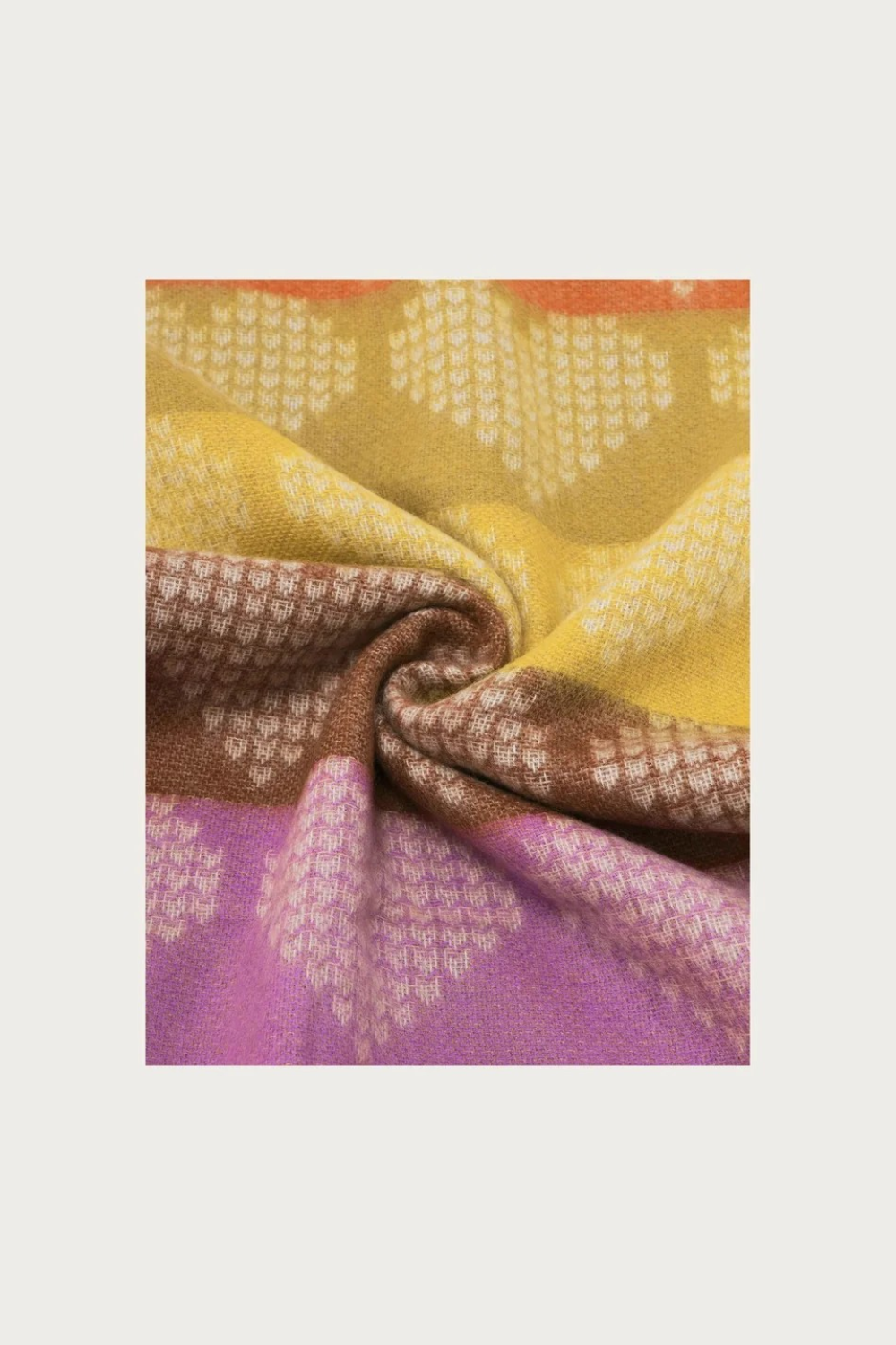Close up of a multi coloured heart printed scarf photographed on a light background.