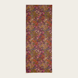 Floral print scarf in shades of burgundy, green, orange and pink photographed on a light backdrop.