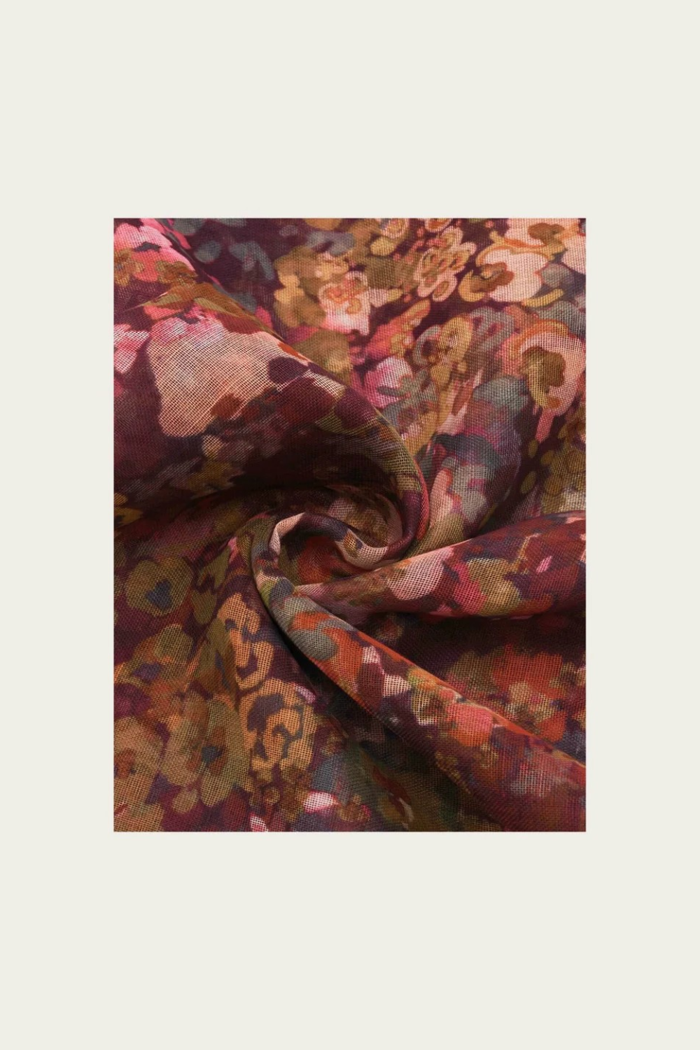 Floral print scarf in shades of burgundy, green, orange and pink photographed on a light backdrop.