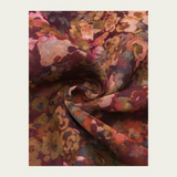 Floral print scarf in shades of burgundy, green, orange and pink photographed on a light backdrop.