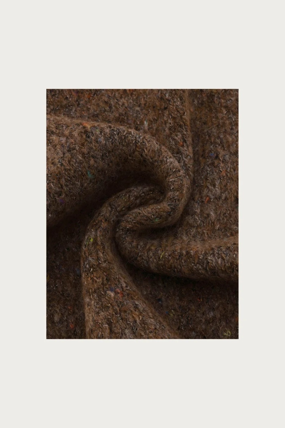 Close up of a brown scarf with multi coloured flecks photographed on a light background.