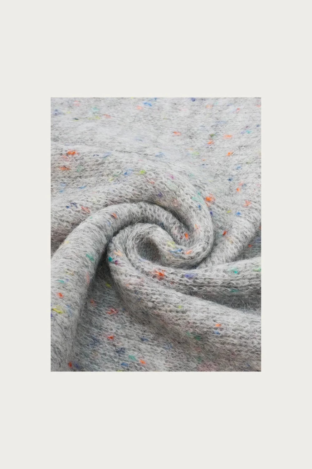 Close up of a grey scarf with multi coloured speckles photographed on a light background.