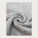 Close up of a grey scarf with multi coloured speckles photographed on a light background.