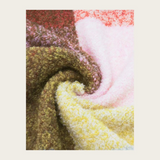 A close up of a multi coloured checkered scarf photographed on a light background.