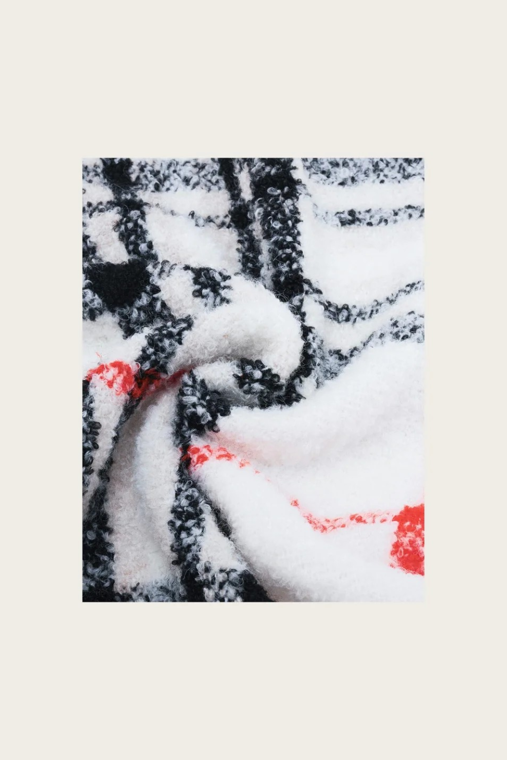 Close up of a cream, black and orange plaid scarf photographed on a light background.
