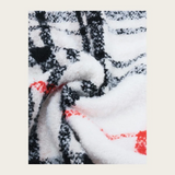 Close up of a cream, black and orange plaid scarf photographed on a light background.