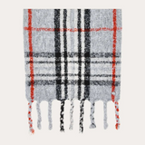 A grey, black and orange plaid scarf with fringe photographed on a light background.