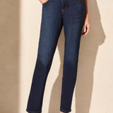 Person wearing dark blue jeans against a beige background