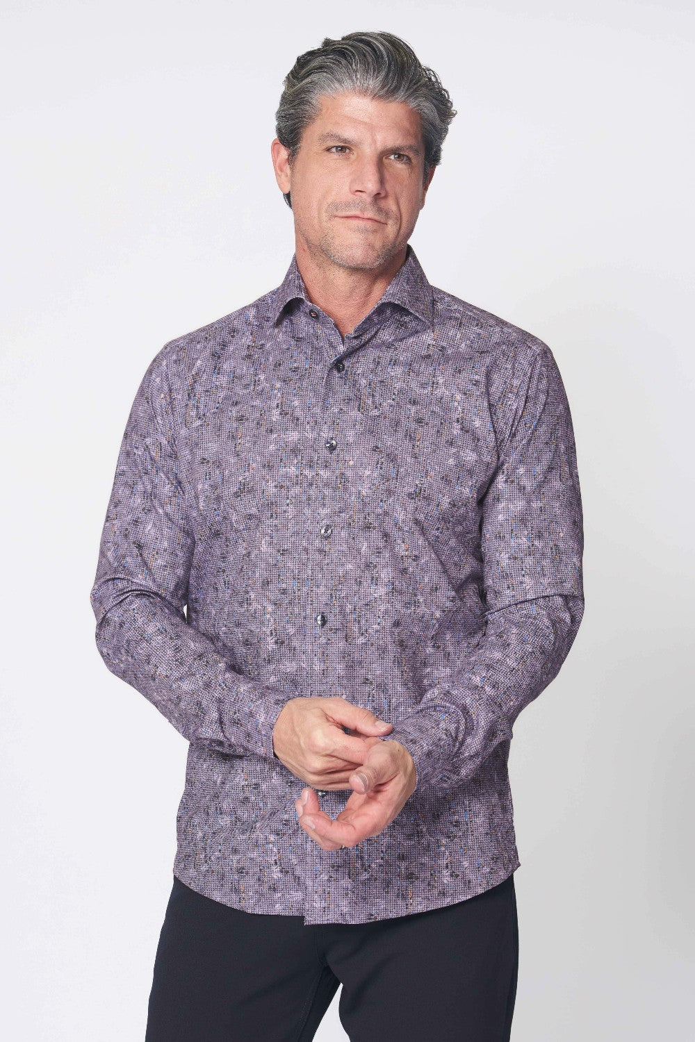 Man wearing a patterned purple shirt against a white background