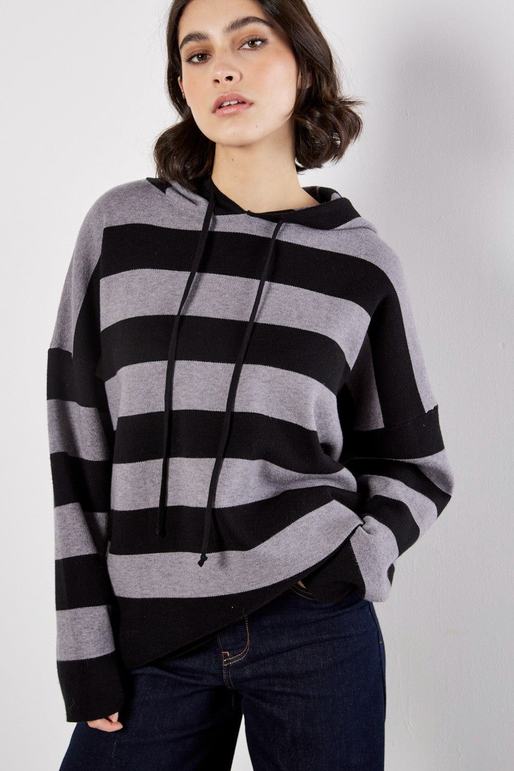 Woman wearing a black and gray striped poncho against a white background