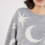 Person wearing a gray sweater with star and moon patterns on a white background