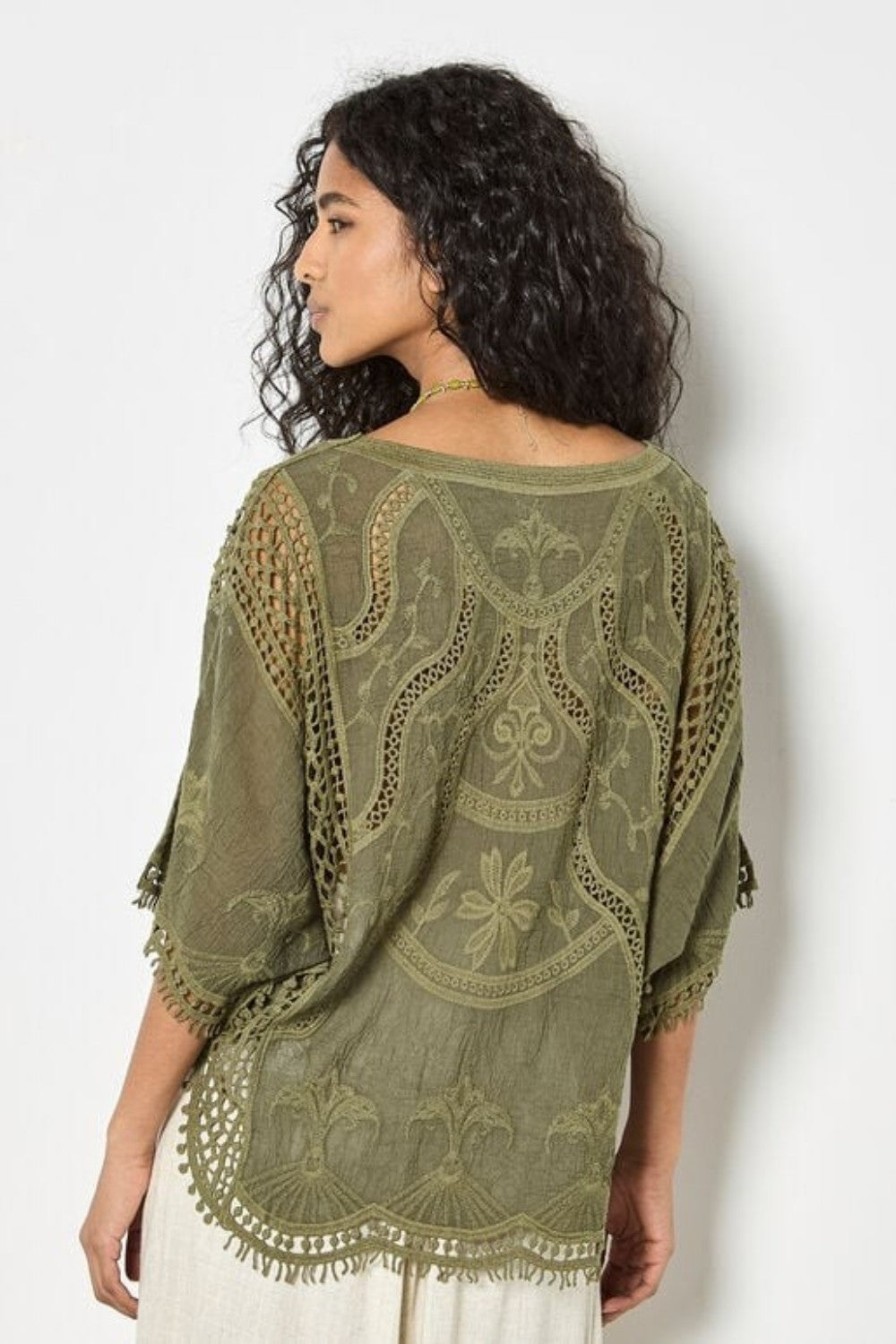Woman wearing a green embroidered shawl against a white background