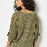 Woman wearing a green embroidered shawl against a white background