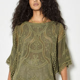 Woman wearing a green embroidered poncho against a white background
