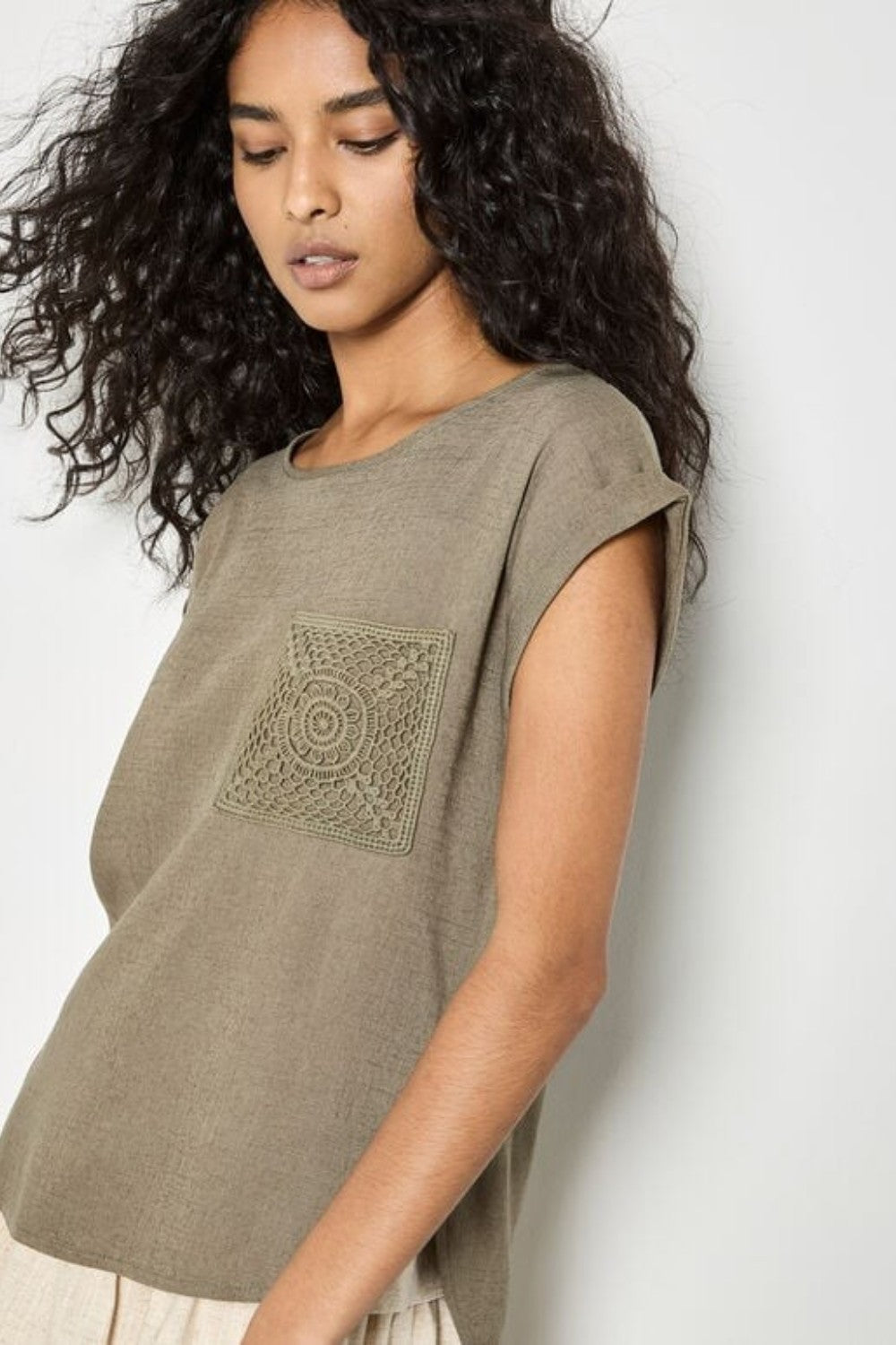 Woman wearing a green t-shirt with a geometric design against a white background