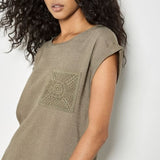 Woman wearing a green t-shirt with a geometric design against a white background