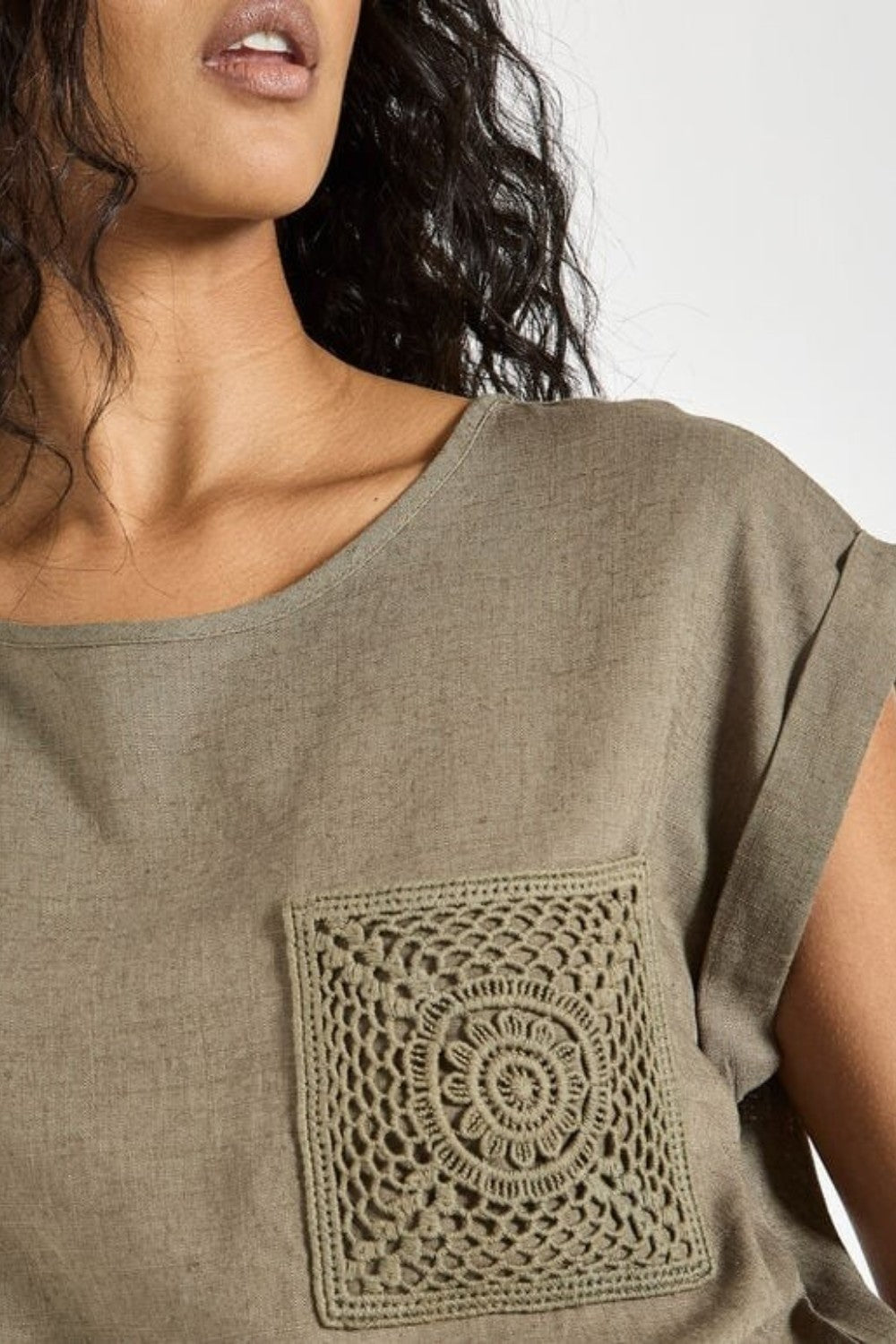 Woman wearing a green t-shirt with a decorative pocket design.