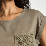 Woman wearing a green t-shirt with a decorative pocket design.