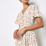 Woman wearing a floral dress against a plain background