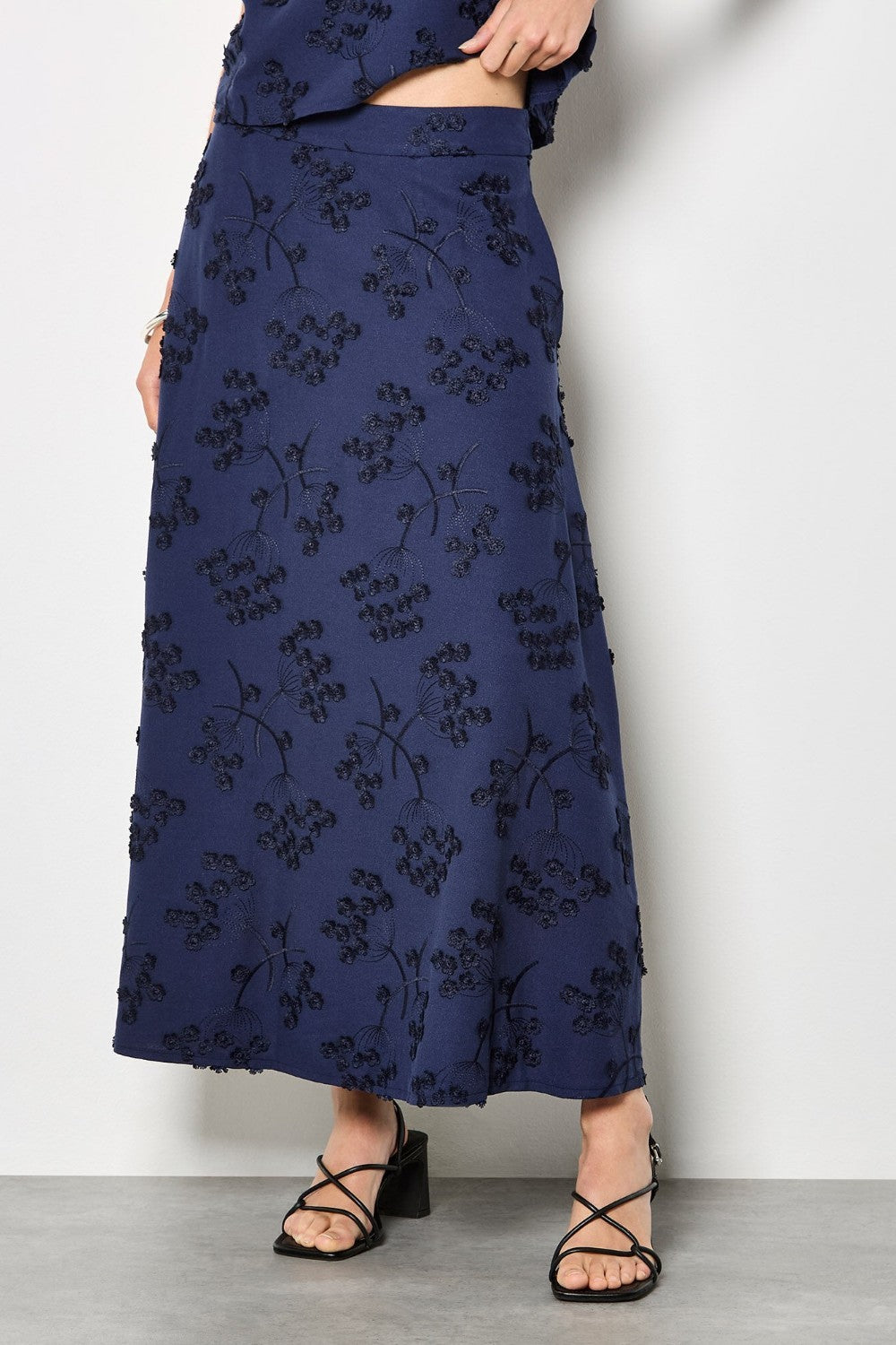Navy blue floral patterned skirt worn by a person on a white background